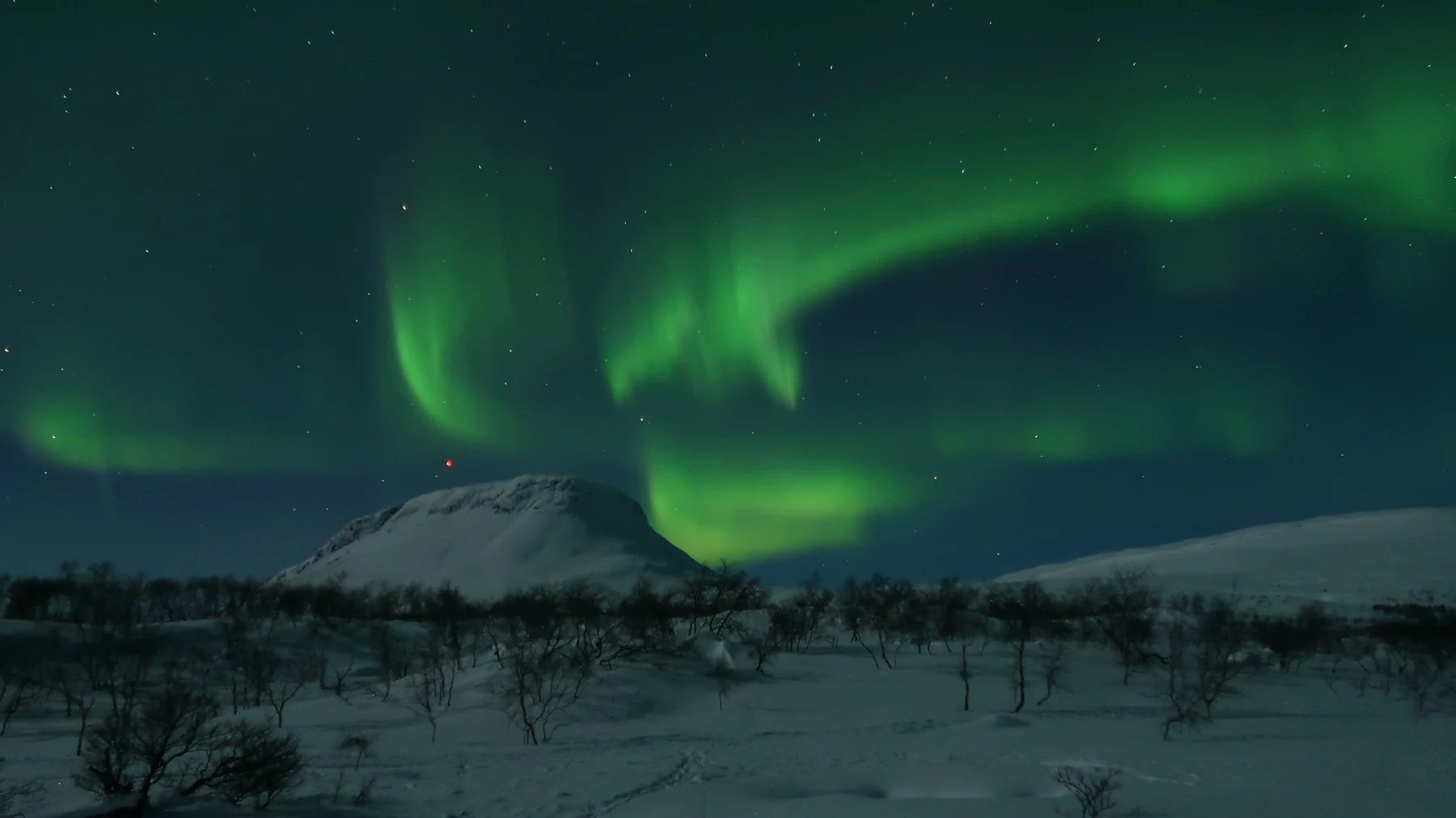 Nordlys over det snedækkede Saana-fjeld i finsk Lapland